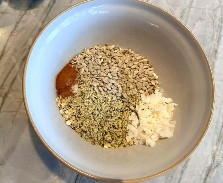 Bowl with oats, cinnamon, sunflower and hemp seeds, coconut, dry ingredients.